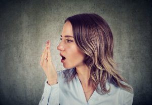 woman doing a hand breath test to check for halitosis